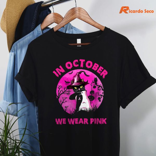 Cat witch in October we wear Pink Breast cancer awareness Halloween T-shirt hanging on a hanger