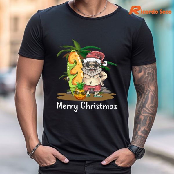Christmas Palm Tree Tropical Xmas Coconut Santa Surfing T-Shirt is being worn on the body