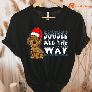 Doodle All The Way Goldendoodle Santa Hat Christmas T-Shirt hung on a hanger